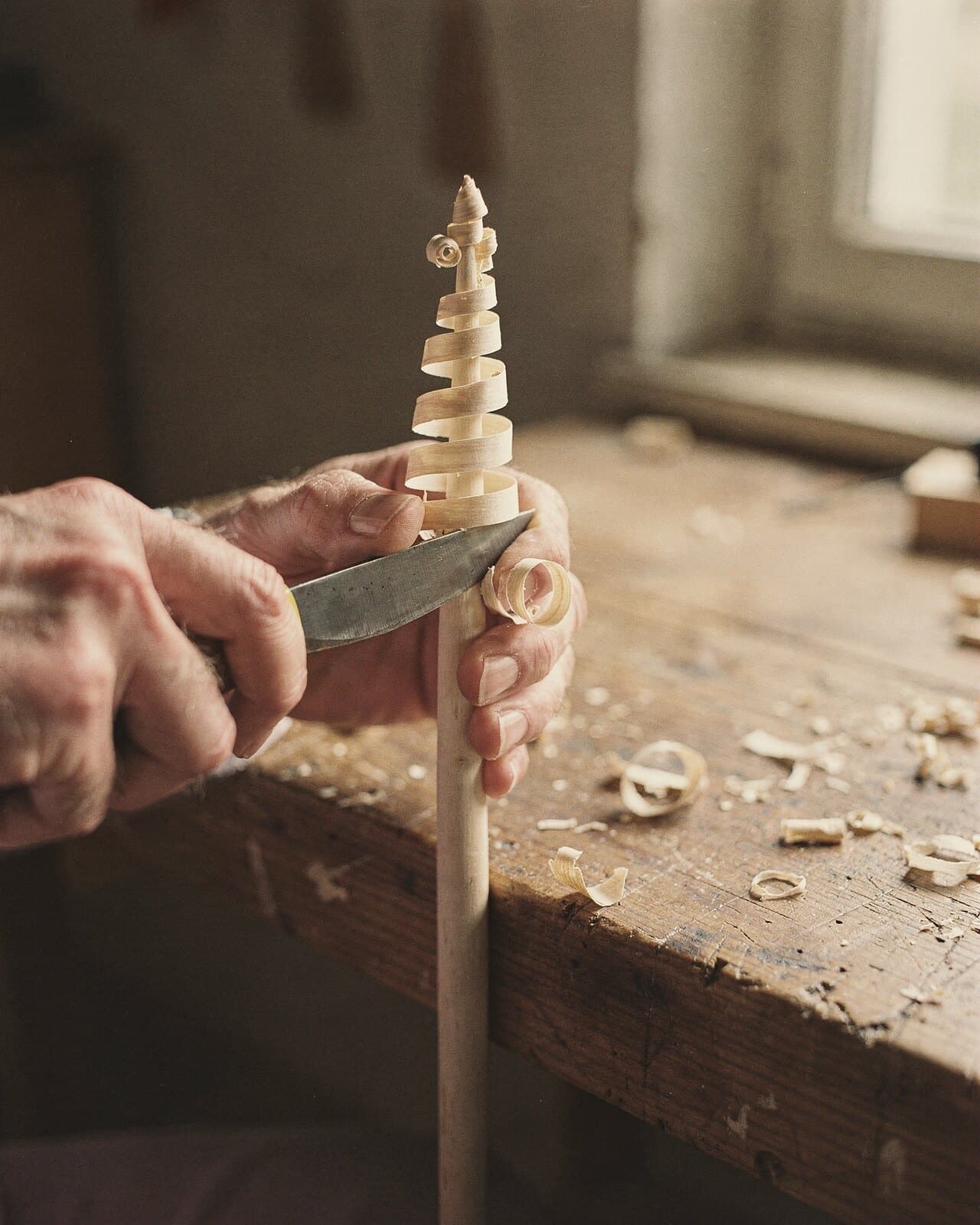 Ein Messer hebt hauchdünne Locken von einem Lindenstab, Stufe um Stufe, und ein Spanbaum entsteht.