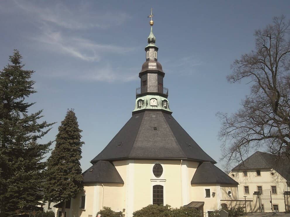 Seiffen's octagonal baroque church with its tiered tower and dark slate roof, framed by spruce trees.