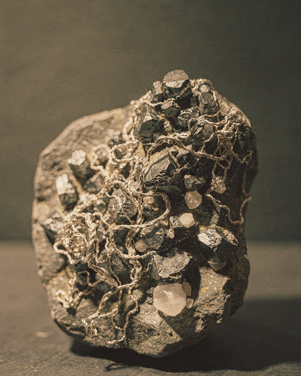 Wire silver curling over dark crystals on a rock specimen.