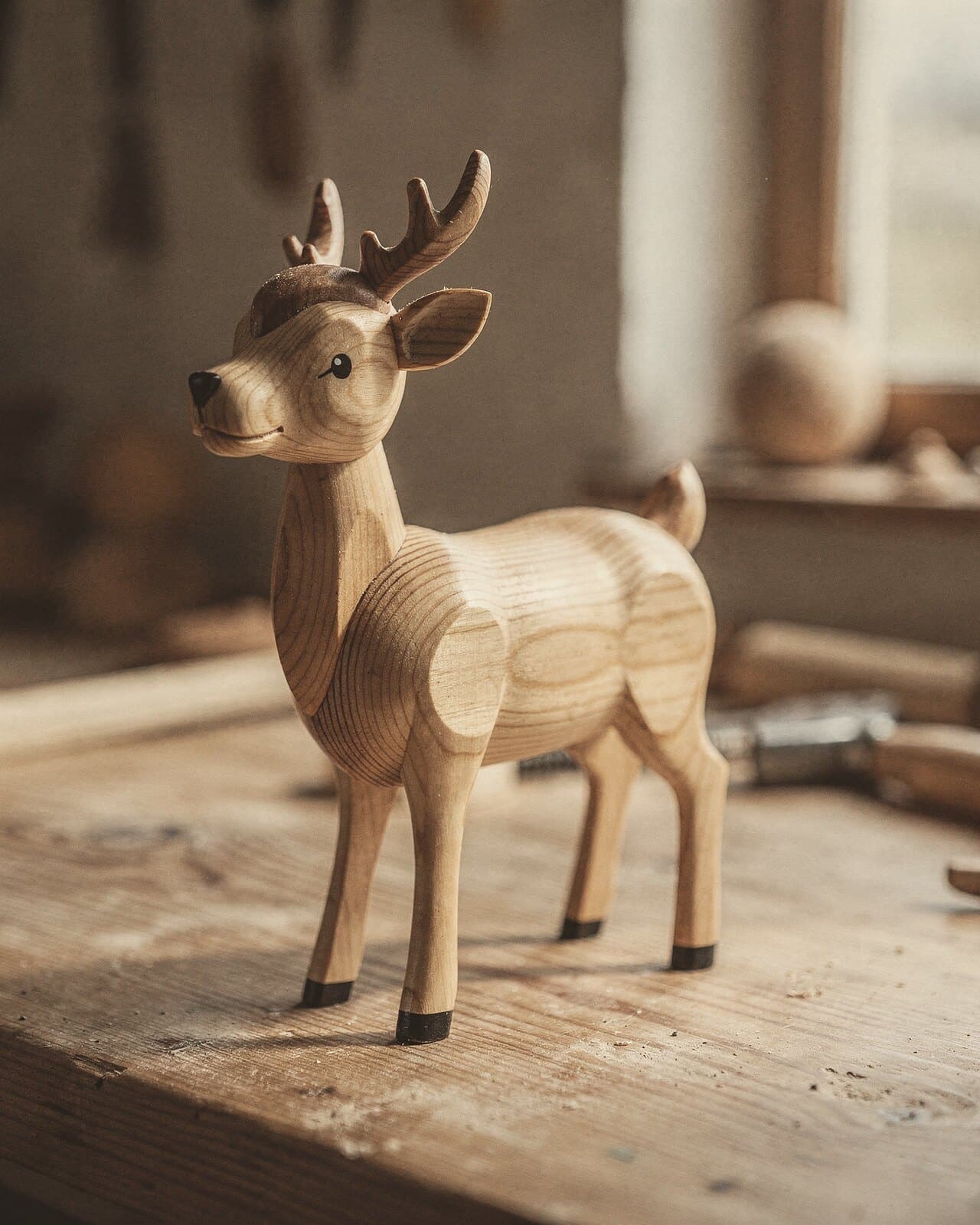 Ein kleiner Holzhirsch, die Jahresringe des Holzes laufen quer über seinen Körper.