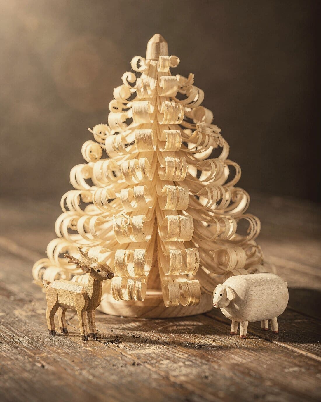 Ein Spanbaum aus gelocktem Lindenholz neben einem kleinen gedrechselten Reh und einem weißen Schaf.